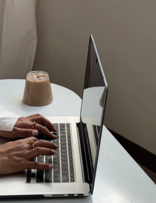 hands on a laptop keyboard with iced coffee